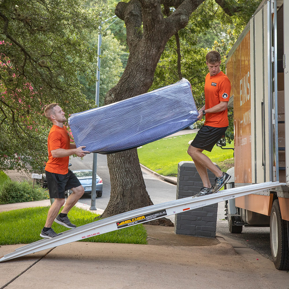 Two Einstein movers load a couch into a moving truck
