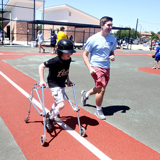 A volunteer runs beside a child using a walker