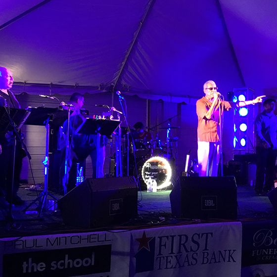 A man speaks into a mircophone while onstage in a brightly light club