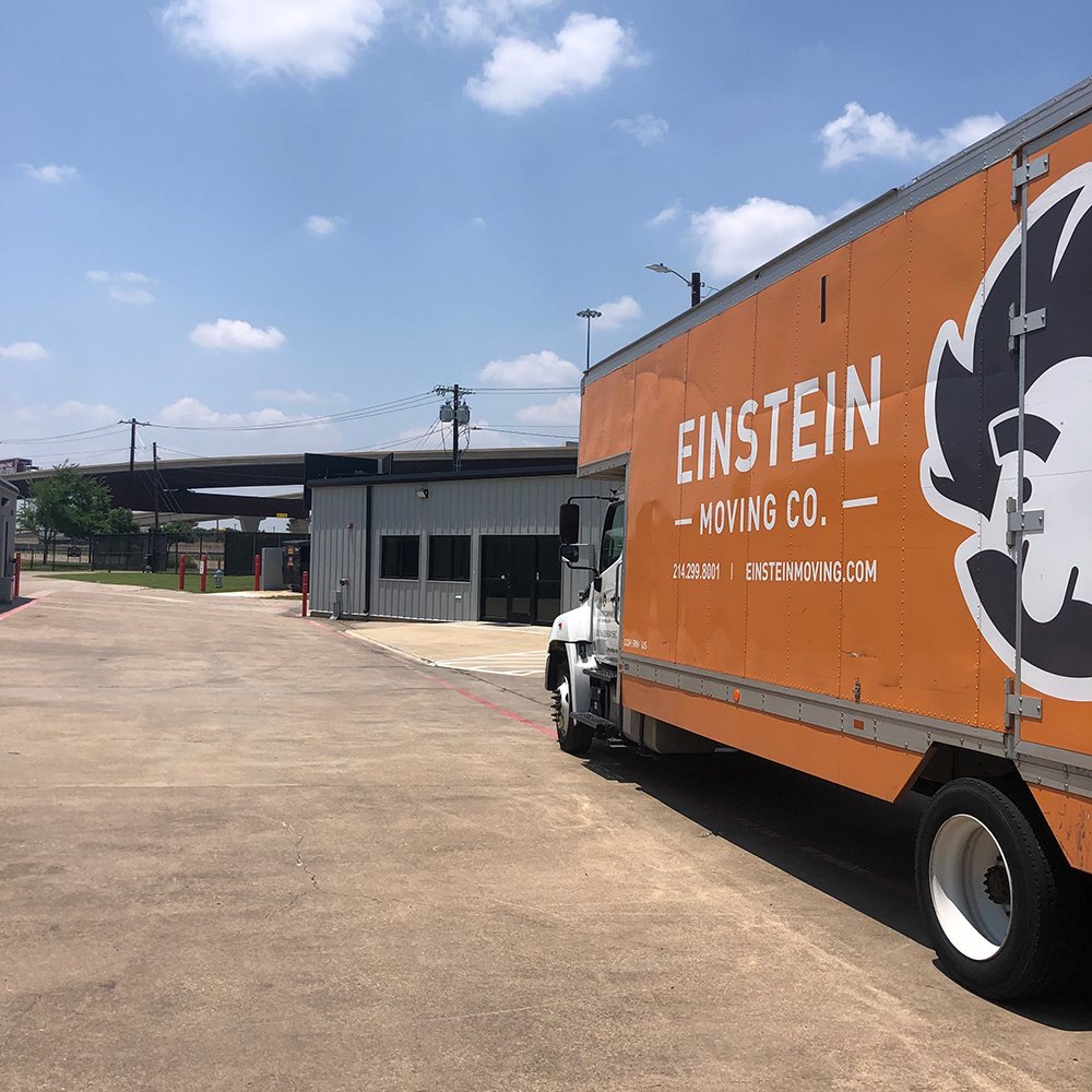 Large orange moving truck parked in front of an office space.