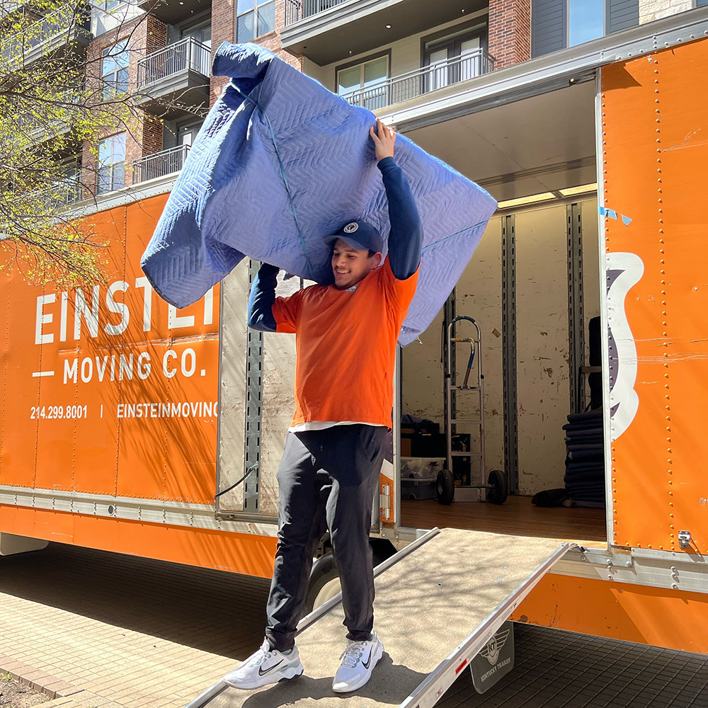 Man carrying furniture out of moving truck, assisting in an apartment move.