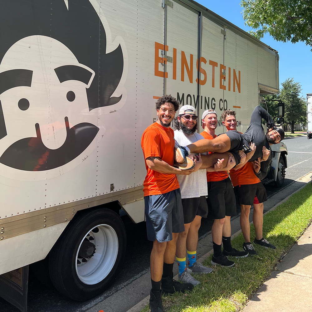 Five North Austin movers posing for a photo in front of the moving truck.