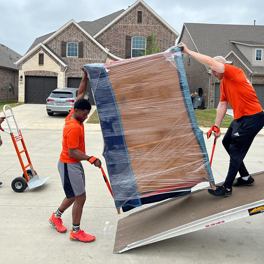Two movers carrying a large piece of furniture.
