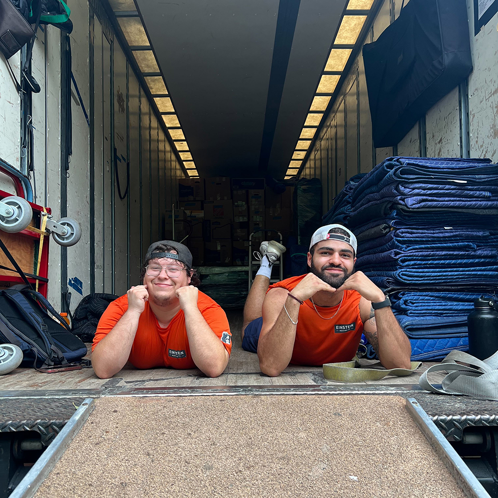 Two movers from Einstein Moving Company playfully posing in the back of a moving truck, ready for their next move in Round Rock, TX.